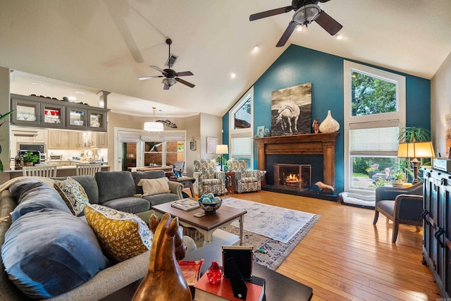 living area featuring ceiling fan, a glass covered fireplace, light wood finished floors, beamed ceiling, and recessed lighting