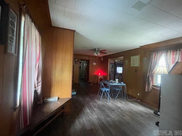 dining space with wood finished floors, a ceiling fan, and wood walls