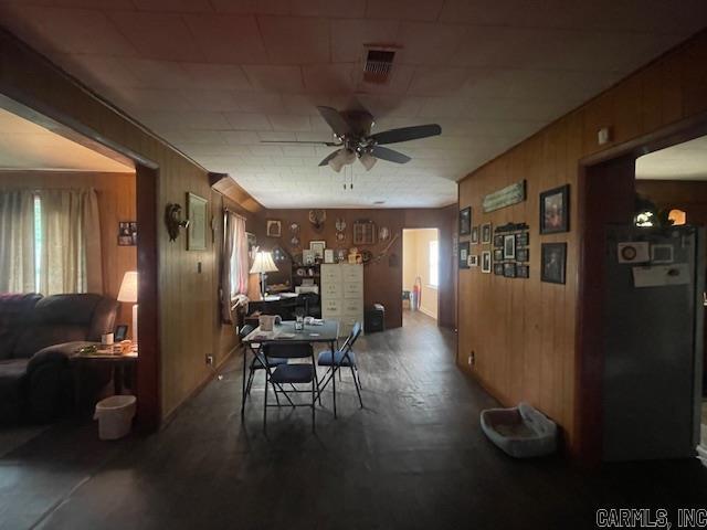 dining space featuring a ceiling fan, wooden walls, and wood finished floors