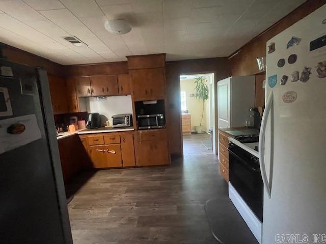 kitchen with freestanding refrigerator, gas range, stainless steel microwave, and light countertops
