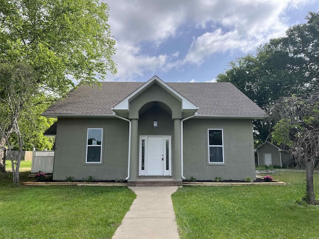 single story home with stucco siding, a front lawn, and a shingled roof