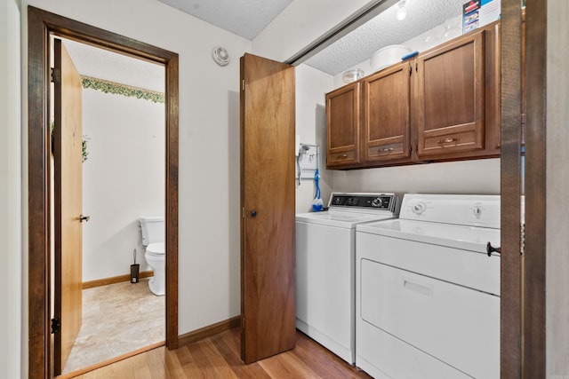 105 Long Island Bay Unit A1, Hot Springs, AR 71913 - laundry room featuring washing machine and clothes dryer, cabinet space, light wood-style flooring, a textured ceiling, and baseboards