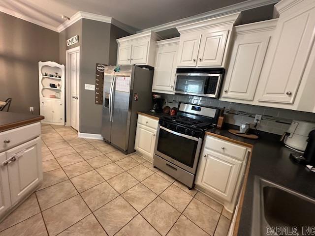 13815 Carrington Place Dr, Alexander, AR 72002 - kitchen with appliances with stainless steel finishes, dark countertops, ornamental molding, decorative backsplash, and light tile patterned floors