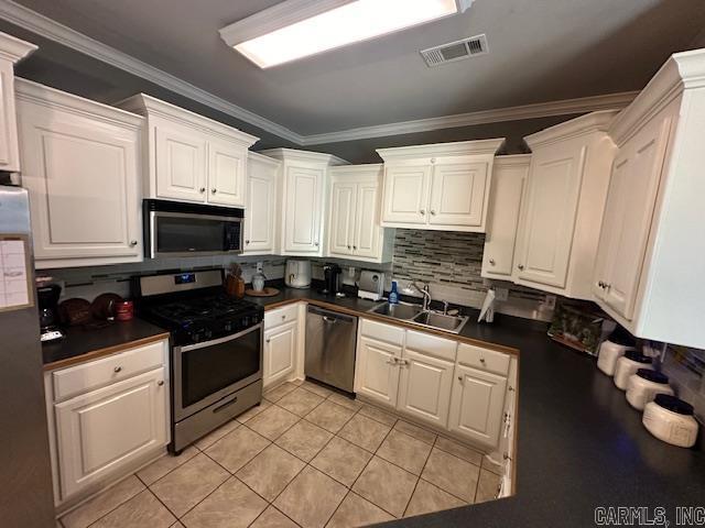 13815 Carrington Place Dr, Alexander, AR 72002 - kitchen featuring stainless steel appliances, dark countertops, backsplash, a sink, and crown molding