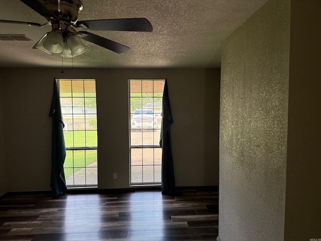 211 Turner St, Mena, AR 71953 - empty room featuring dark wood-style flooring, a textured ceiling, a ceiling fan, and a textured wall