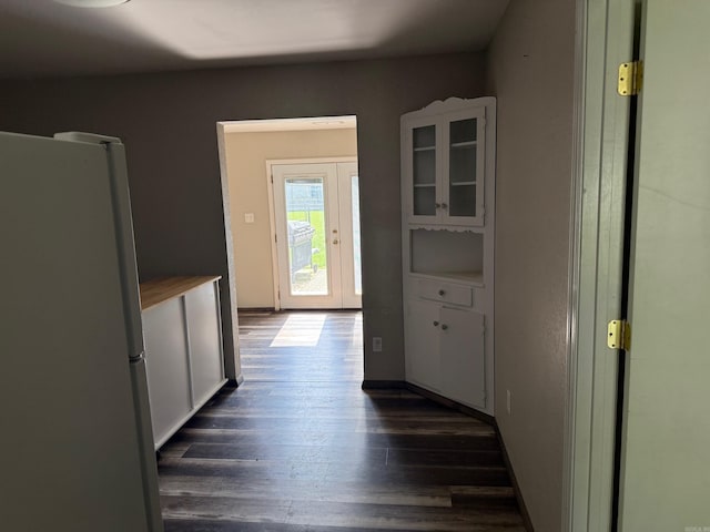 211 Turner St, Mena, AR 71953 - kitchen featuring freestanding refrigerator, dark wood-style flooring, glass insert cabinets, and white cabinetry
