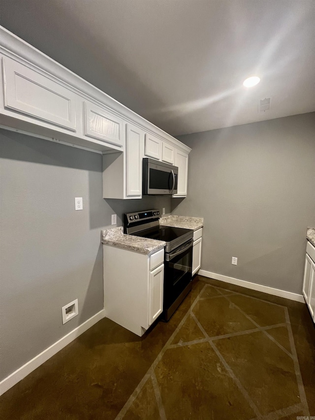 233 Iris, Benton, AR 72015 - kitchen with stainless steel microwave, electric stove, white cabinetry, and baseboards
