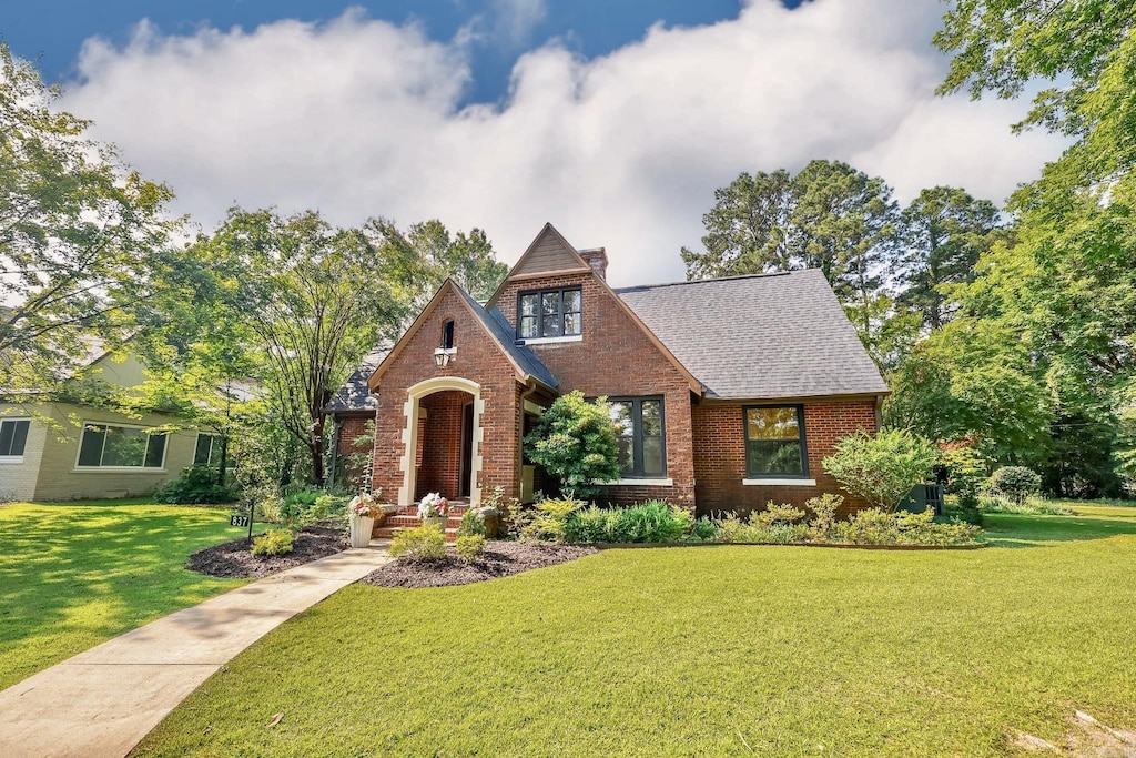 837 Maple St, Camden, AR 71701 - tudor house with brick siding, a front yard, a chimney, and a shingled roof