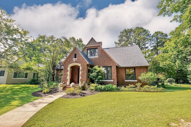 837 Maple St, Camden, AR 71701 - tudor house with brick siding, a front yard, a chimney, and a shingled roof