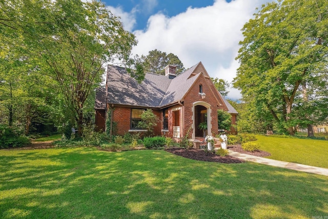 837 Maple St, Camden, AR 71701 - tudor-style house with brick siding, a front yard, and a chimney