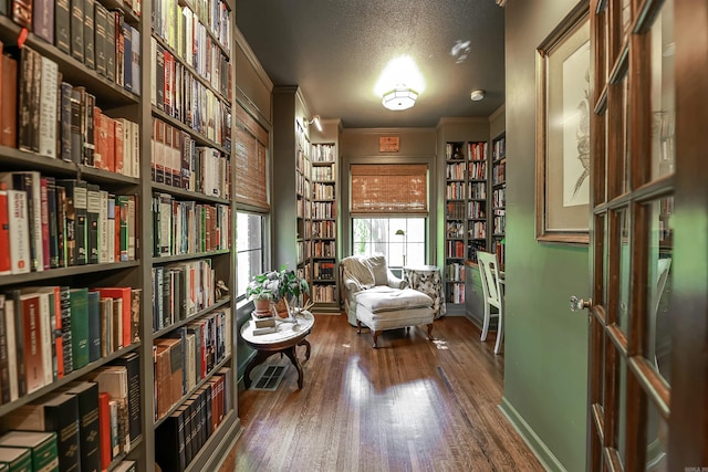 837 Maple St, Camden, AR 71701 - sitting room featuring wall of books, wood finished floors, baseboards, crown molding, and a textured ceiling