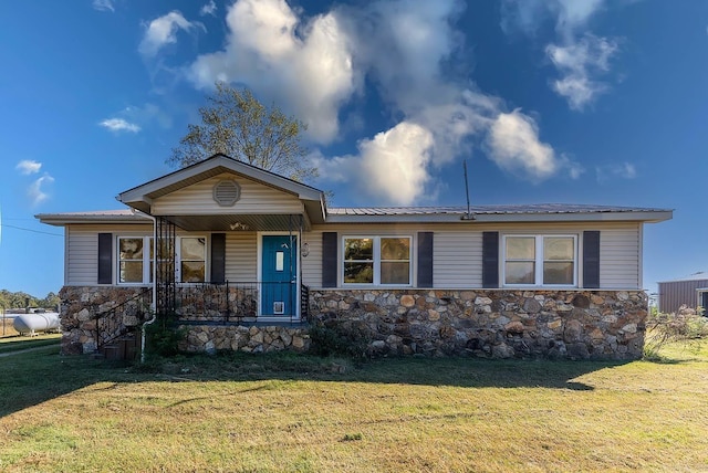 single story home featuring stone siding, covered porch, a front lawn, and metal roof