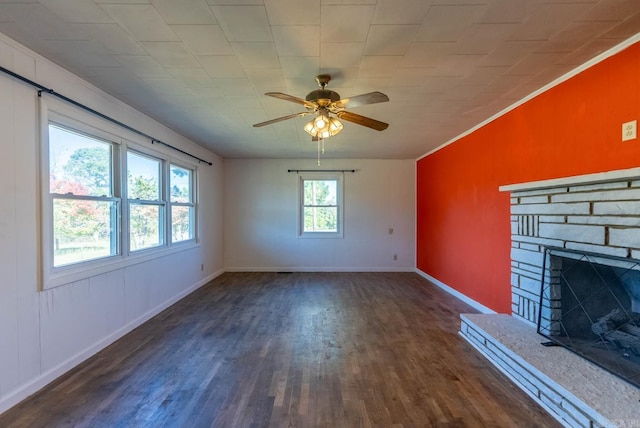unfurnished living room with dark wood finished floors, a ceiling fan, crown molding, baseboards, and a fireplace with raised hearth