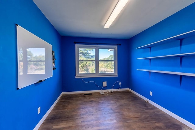 empty room with dark wood finished floors and baseboards
