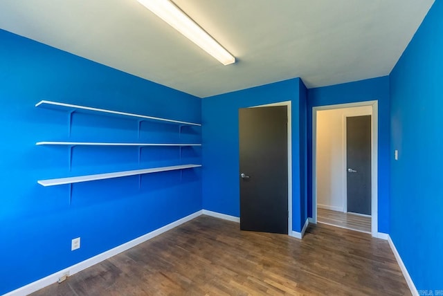 unfurnished bedroom with dark wood-style flooring and baseboards