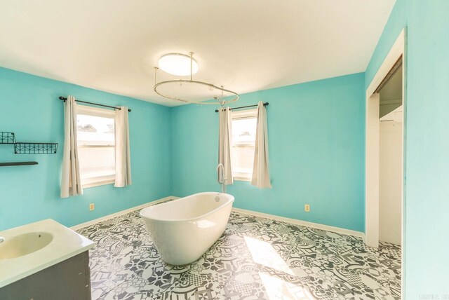 full bathroom featuring healthy amount of natural light, a soaking tub, vanity, and baseboards