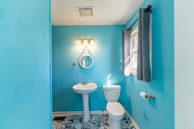 half bathroom featuring toilet, baseboards, a sink, and tile patterned floors