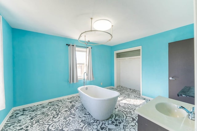 bathroom with a soaking tub, vanity, and baseboards