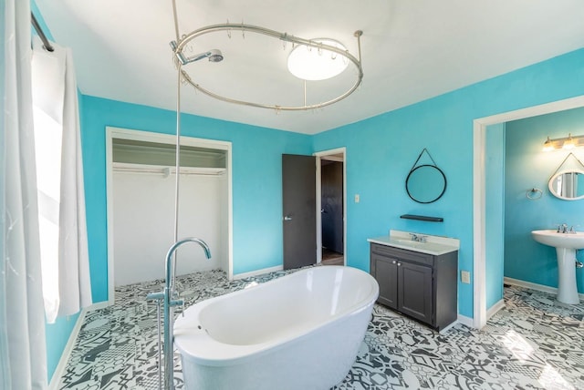 full bath with a freestanding bath, a sink, and baseboards
