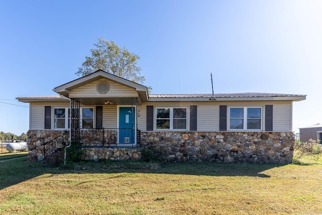 single story home featuring stone siding, covered porch, a front lawn, and metal roof