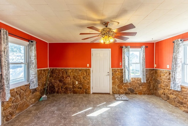 unfurnished room with wainscoting, crown molding, and ceiling fan