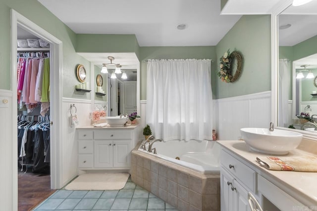 111 Country Oaks Dr, Malvern, AR 72104 - bathroom with a wainscoted wall, two vanities, a tub with jets, tile patterned floors, and a decorative wall