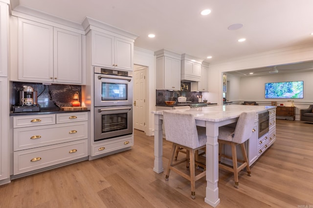 40 Tennyson Ct, North Little Rock, AR 72116 - kitchen with double oven, crown molding, tasteful backsplash, a kitchen bar, and light stone counters