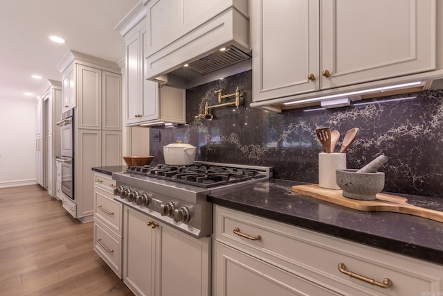 40 Tennyson Ct, North Little Rock, AR 72116 - kitchen with stainless steel appliances, premium range hood, tasteful backsplash, light wood-style floors, and white cabinets