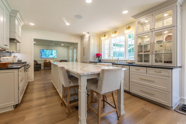 40 Tennyson Ct, North Little Rock, AR 72116 - kitchen with a kitchen island, a breakfast bar area, light wood-style flooring, crown molding, and a sink