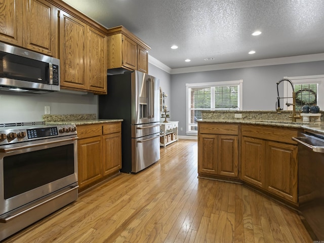 57 Excelso Way, Hot Springs Village, AR 71909 - kitchen with appliances with stainless steel finishes, a sink, brown cabinets, crown molding, and light wood-style flooring