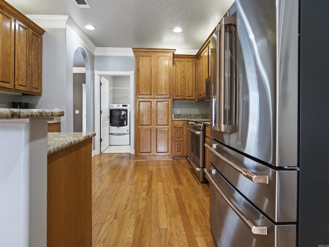 57 Excelso Way, Hot Springs Village, AR 71909 - kitchen featuring appliances with stainless steel finishes, washer / clothes dryer, crown molding, brown cabinets, and light wood-style floors
