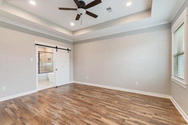 1569 Marquee Cir, Cabot, AR 72023 - unfurnished bedroom featuring a barn door, wood finished floors, a tray ceiling, baseboards, and recessed lighting