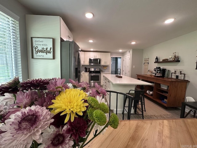 9 Whispering Dr, Alexander, AR 72002 - kitchen featuring stainless steel appliances, white cabinets, light wood finished floors, a kitchen island, and recessed lighting