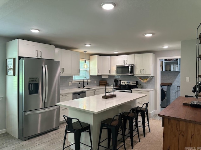 9 Whispering Dr, Alexander, AR 72002 - kitchen with stainless steel appliances, a sink, a breakfast bar area, white cabinets, and recessed lighting