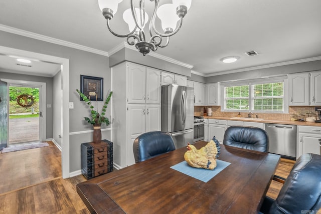15621 Mail Route Rd, Little Rock, AR 72206 - dining space with wood finished floors, a chandelier, healthy amount of natural light, baseboards, and ornamental molding