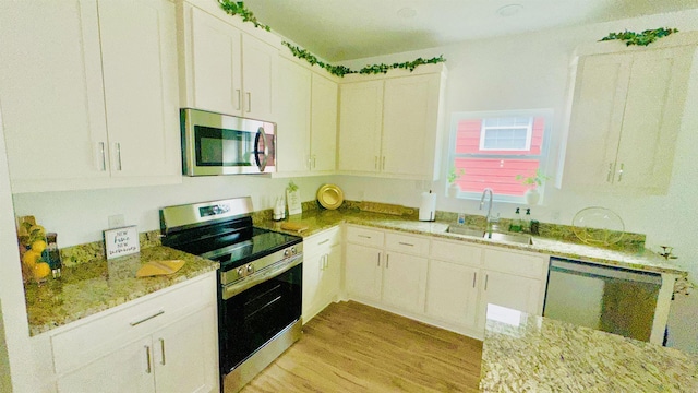 1418 S Martin St, Little Rock, AR 72204 - kitchen with appliances with stainless steel finishes, a sink, light wood-style floors, light stone counters, and white cabinets
