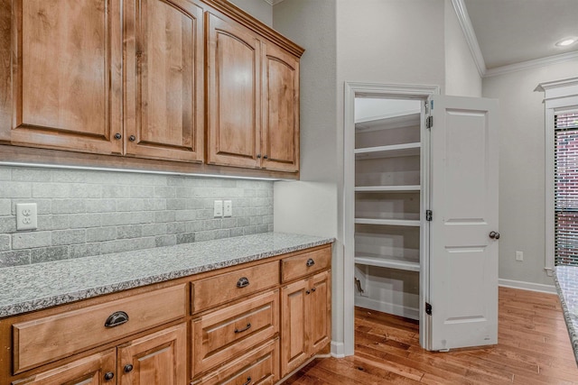26 Kanis Creek Pl, Little Rock, AR 72223 - kitchen featuring ornamental molding, light wood-type flooring, tasteful backsplash, light stone counters, and baseboards
