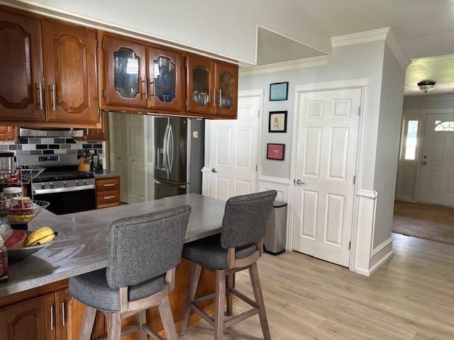 1803 Fairwater Cir, Horseshoe Bend, AR 72512 - kitchen featuring appliances with stainless steel finishes, crown molding, a kitchen breakfast bar, glass insert cabinets, and range hood