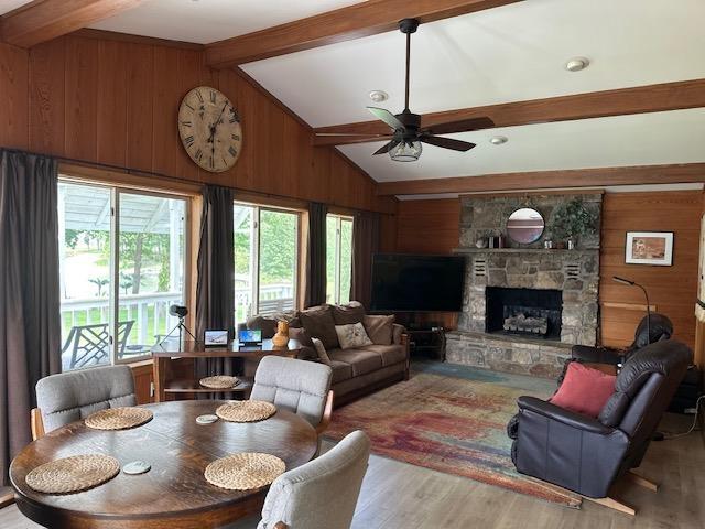 1803 Fairwater Cir, Horseshoe Bend, AR 72512 - living room with wooden walls, wood finished floors, a ceiling fan, and a fireplace