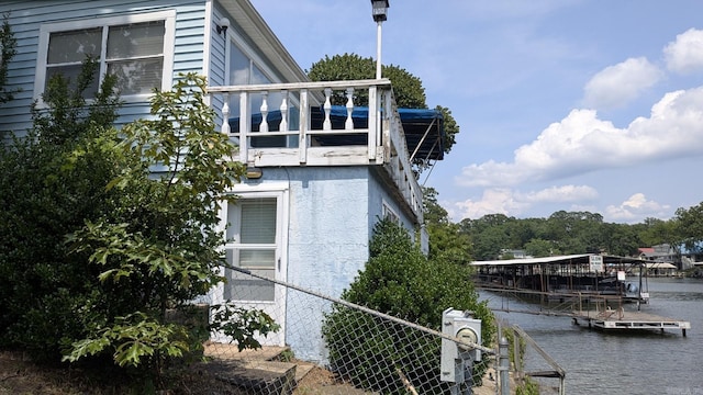 view of side of property with stucco siding, a dock, and a water view