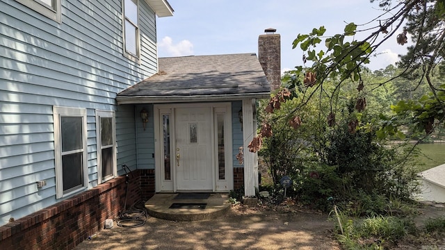 property entrance with roof with shingles and a chimney