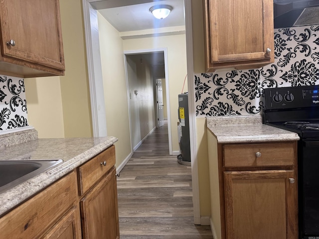 1316-1318 W 13th St, Little Rock, AR 72202 - kitchen with black range with electric stovetop, ventilation hood, dark wood-style floors, light countertops, and brown cabinetry
