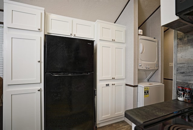 193 Sycamore, Sheridan, AR 72150 - kitchen with freestanding refrigerator, stacked washing machine and dryer, white cabinets, and dark countertops