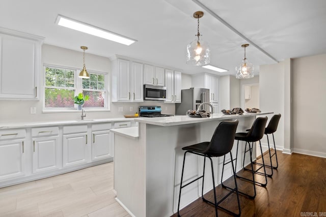 104 Dickson Dr, Little Rock, AR 72207 - kitchen with stainless steel appliances, white cabinetry, light countertops, and hanging light fixtures