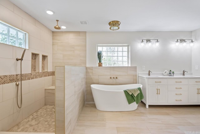 104 Dickson Dr, Little Rock, AR 72207 - bathroom with a freestanding tub, walk in shower, tile walls, double vanity, and recessed lighting