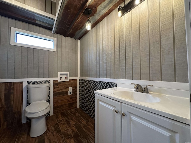 12017 Miller County 10, Fouke, AR 71837 - bathroom with wood finished floors, toilet, vanity, wooden walls, and a wainscoted wall