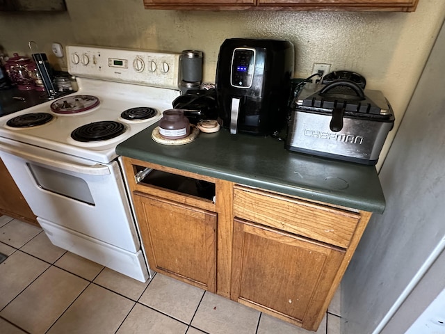 422 Mimosa Rd, North Little Rock, AR 72117 - kitchen with white electric range, light tile patterned flooring, and brown cabinetry