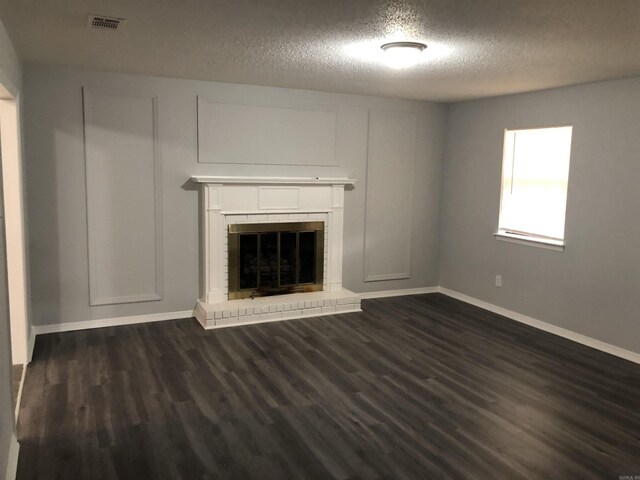6 Bryan Keith Ct, Little Rock, AR 72206 - unfurnished living room featuring a textured ceiling, dark wood-style flooring, a brick fireplace, and baseboards