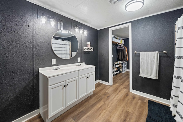508 W Bell, Sheridan, AR 72150 - full bathroom featuring a textured wall, wood finished floors, double vanity, baseboards, and a walk in closet