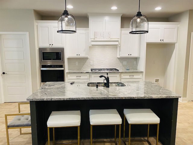 5104 Peace Ln, Alexander, AR 72002 - kitchen featuring stainless steel appliances, a sink, backsplash, white cabinets, and a kitchen bar